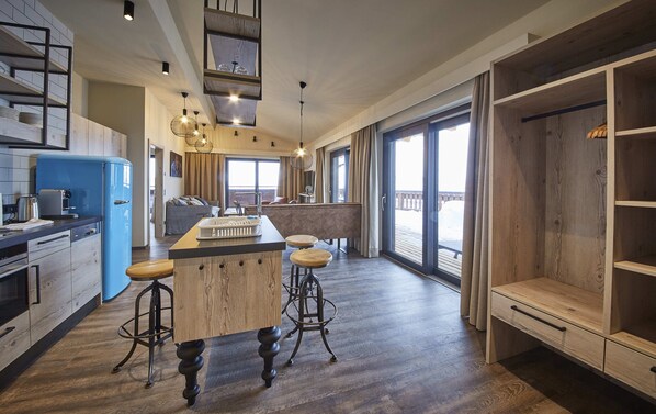 Cocina moderna con una isla central, taburetes de bar y vistas al exterior.