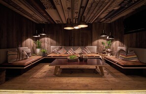 Un rincón de sala acogedor y rústico, con paredes de madera, una mesa de centro de madera y dos sofás con cojines a rayas.