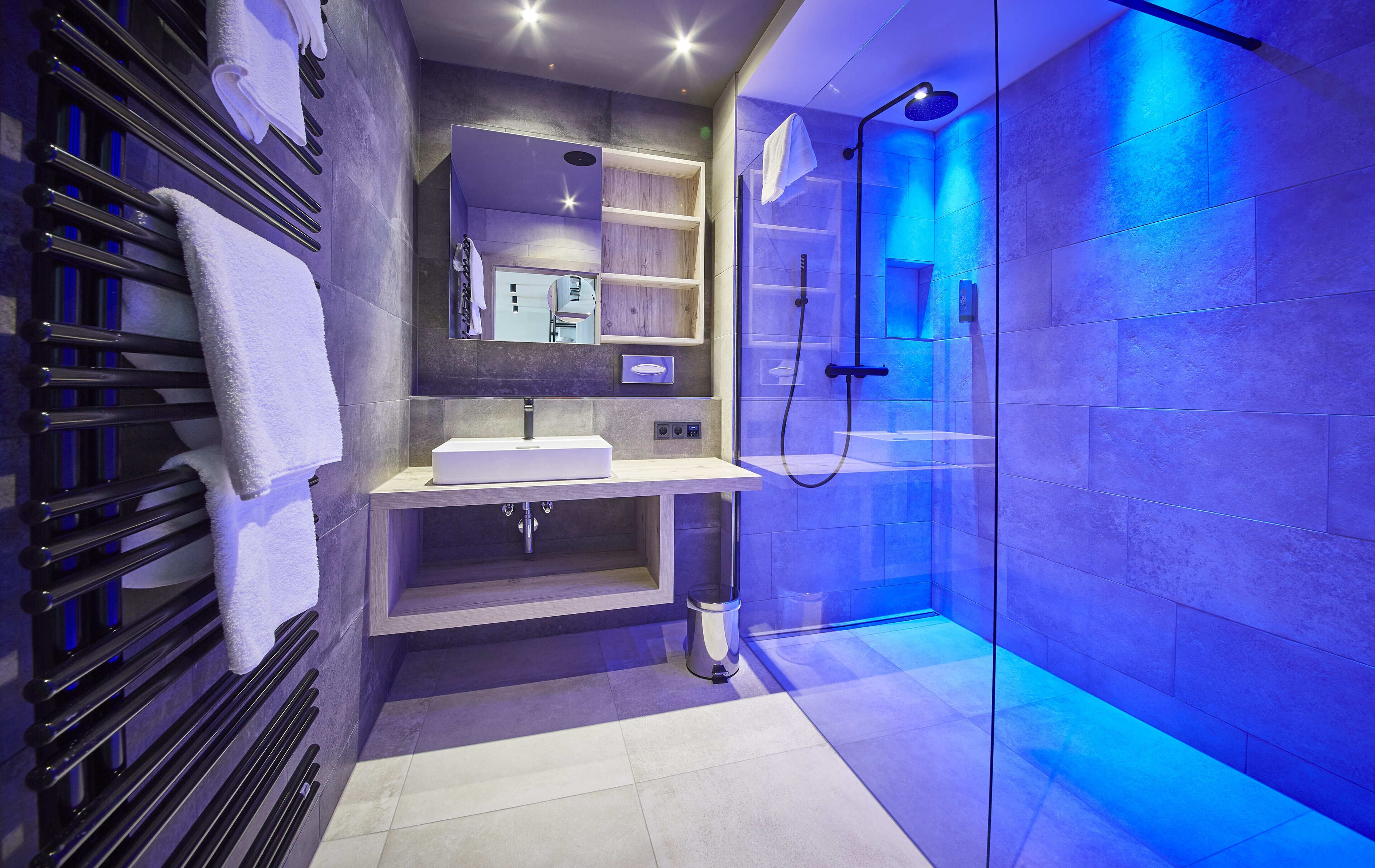 A modern bathroom with a glass-enclosed shower, a white sink, and a towel rack.