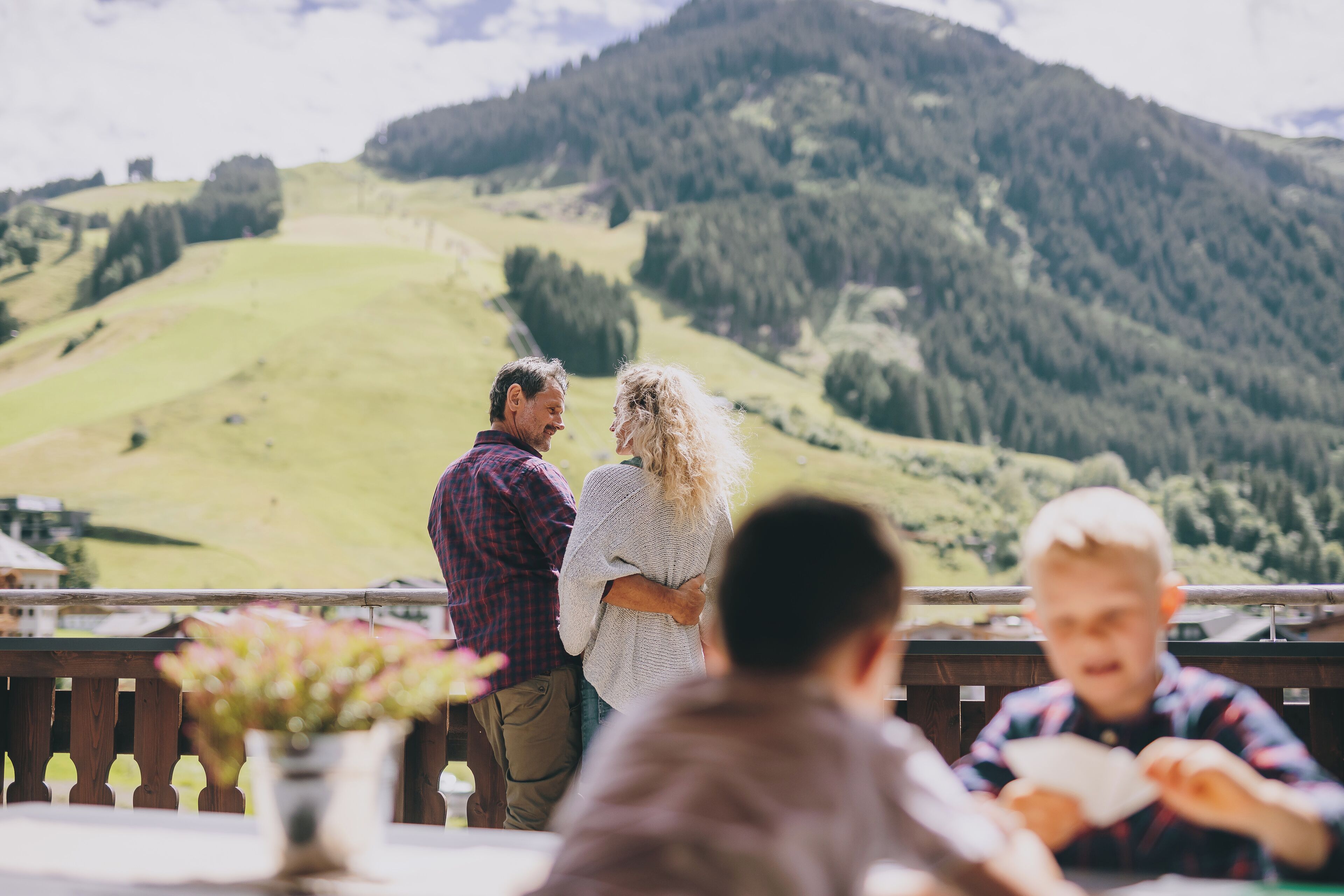 A group of people at a table with a view of a mountainous landscape.