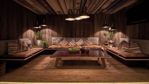 Un rincón de sala acogedor y rústico, con paredes de madera, una mesa de centro de madera y dos sofás con cojines a rayas.
