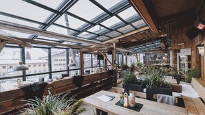 Un restaurante acogedor con interiores de madera, ventanas amplias y plantas de interior.