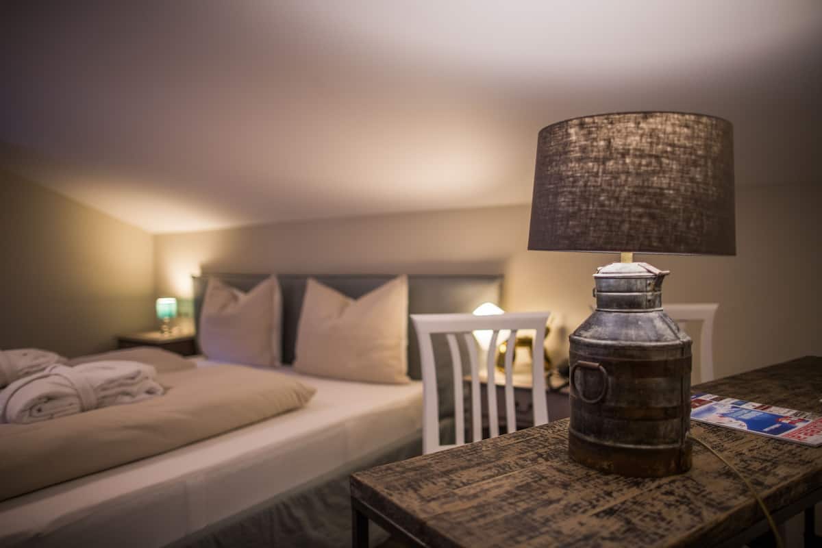 Een slaapkamer met een bed, nachtkastje, lamp en een tafel met een metalen bak.