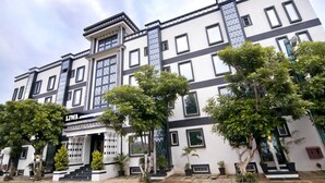 Un hotel de varios pisos con un diseño arquitectónico moderno, que presenta una entrada destacada con escalones, ventanas amplias y un letrero.