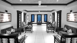 Un vestíbulo amplio con techos altos, ventanas con diseños y mobiliario tradicional.