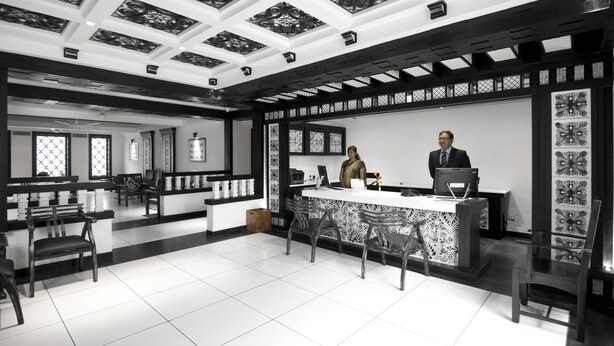 Un moderno vestíbulo de hotel con mostrador de recepción, zona de estar y diseños decorativos en el techo.