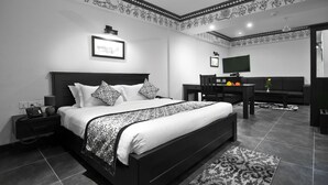 Un dormitorio moderno con una cama grande, un escritorio, un televisor y un techo con diseño.