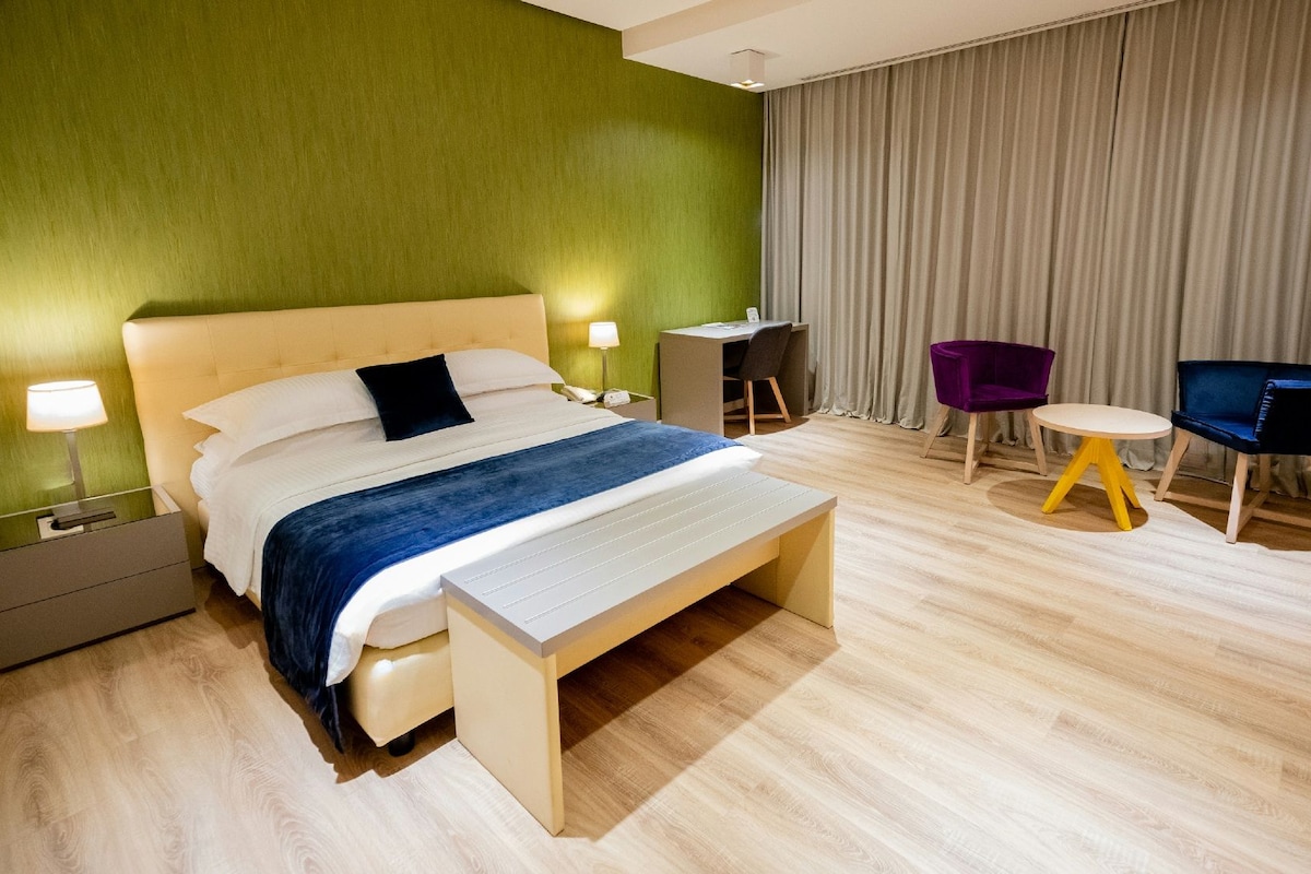 Una habitación de hotel con una cama, mesitas de noche, un escritorio y dos sillas.
