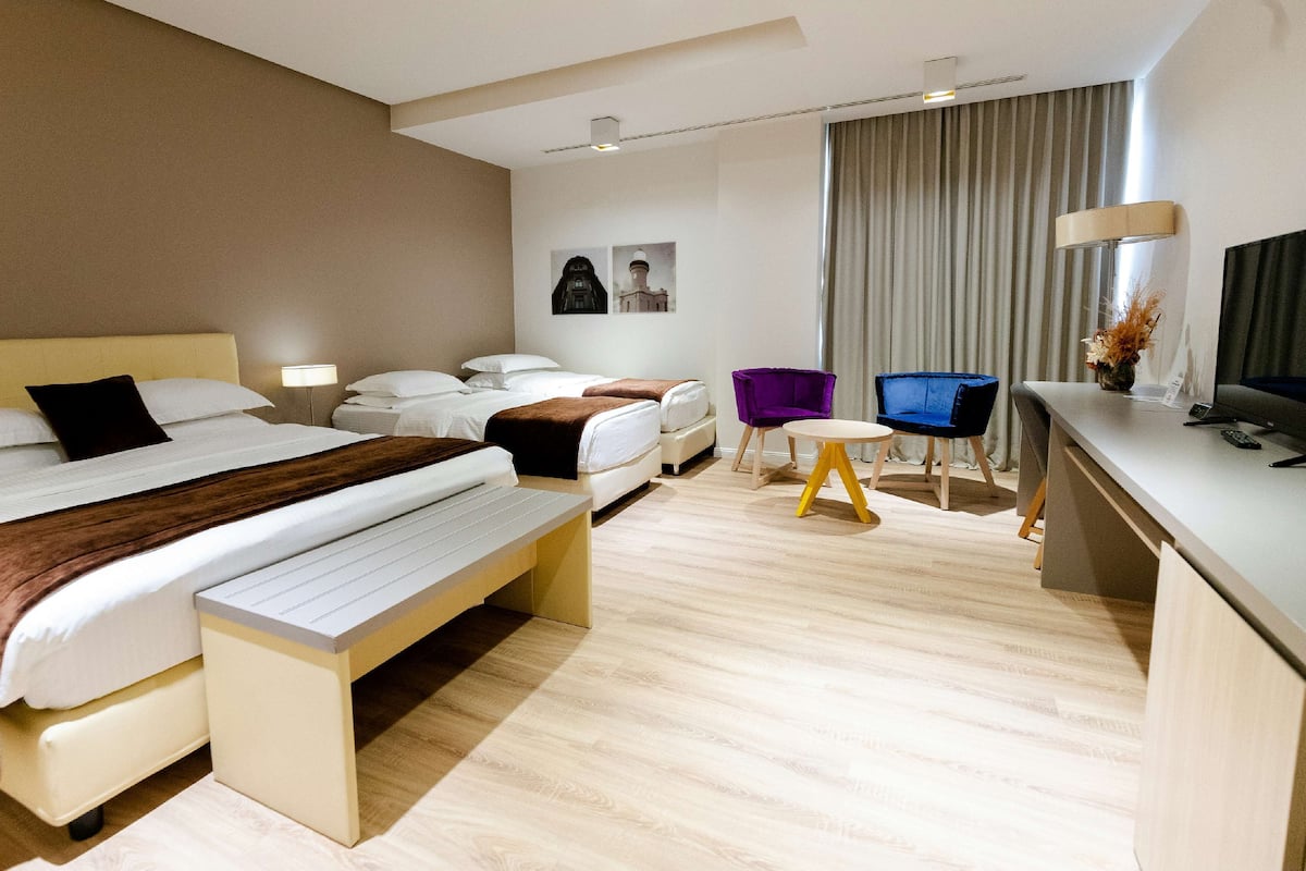 A hotel room with a large bed, a desk, a chair, and a TV.