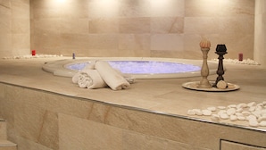 Un espace bien-être comprenant un jacuzzi, des serviettes, des bougies et des pierres décoratives.