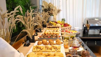 Un bufé con diversos alimentos, entre ellos pasteles, frutas y salsas.