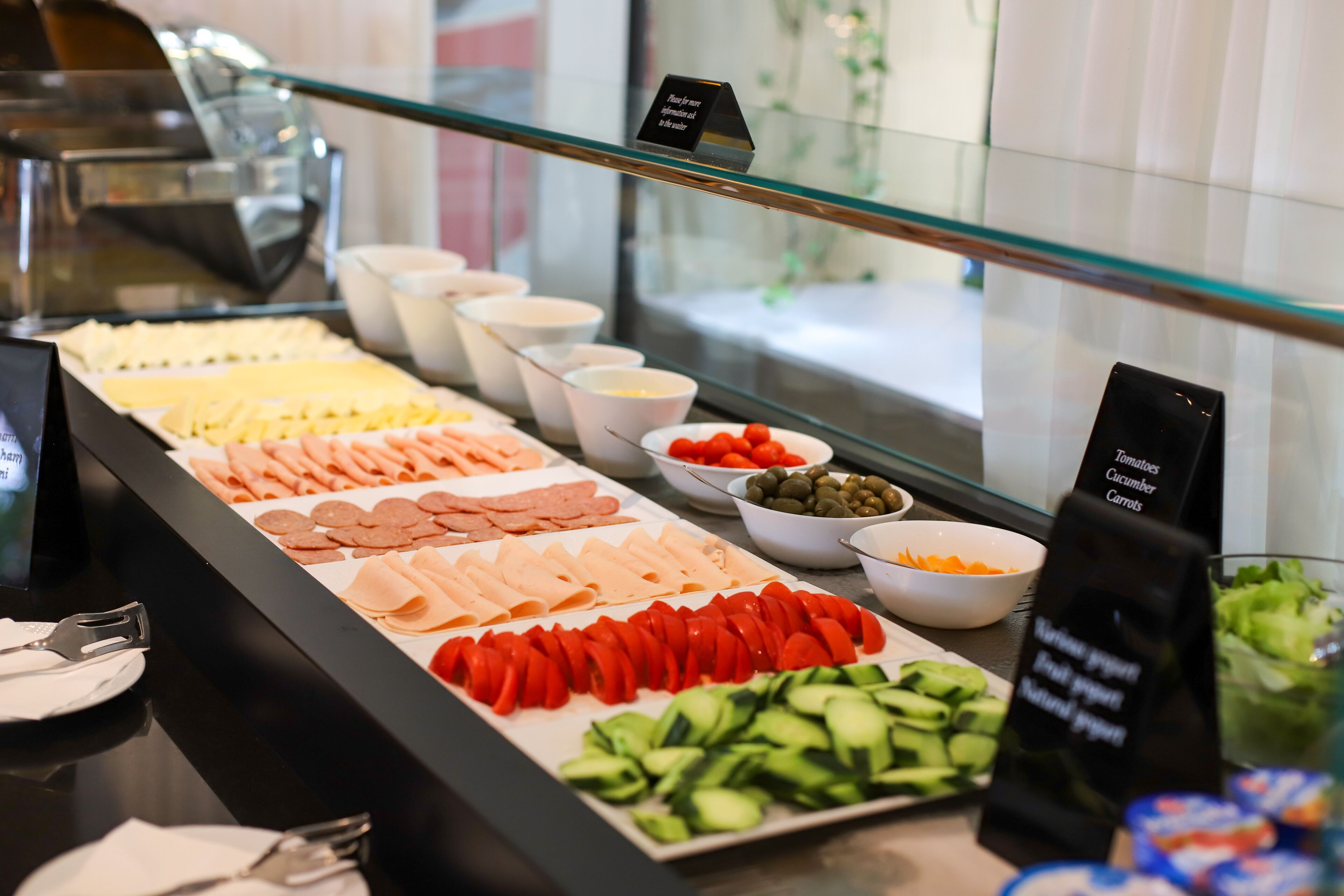 A buffet with various food items including meats, cheeses, and vegetables.