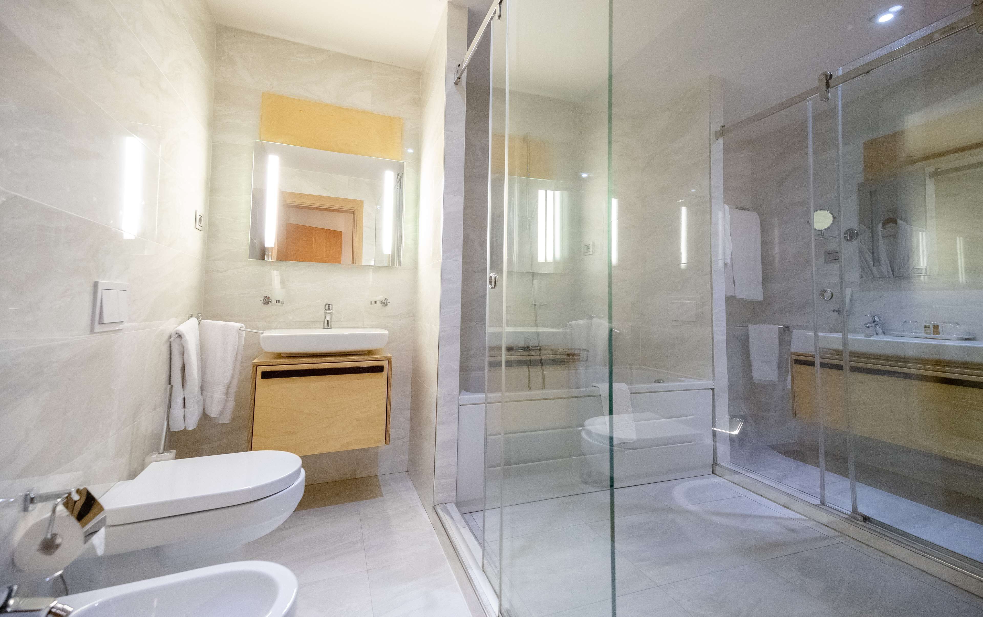 Un baño moderno con ducha envuelta en vidrio, lavamanos e inodoro.