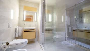 Un baño moderno con ducha envuelta en vidrio, lavamanos e inodoro.