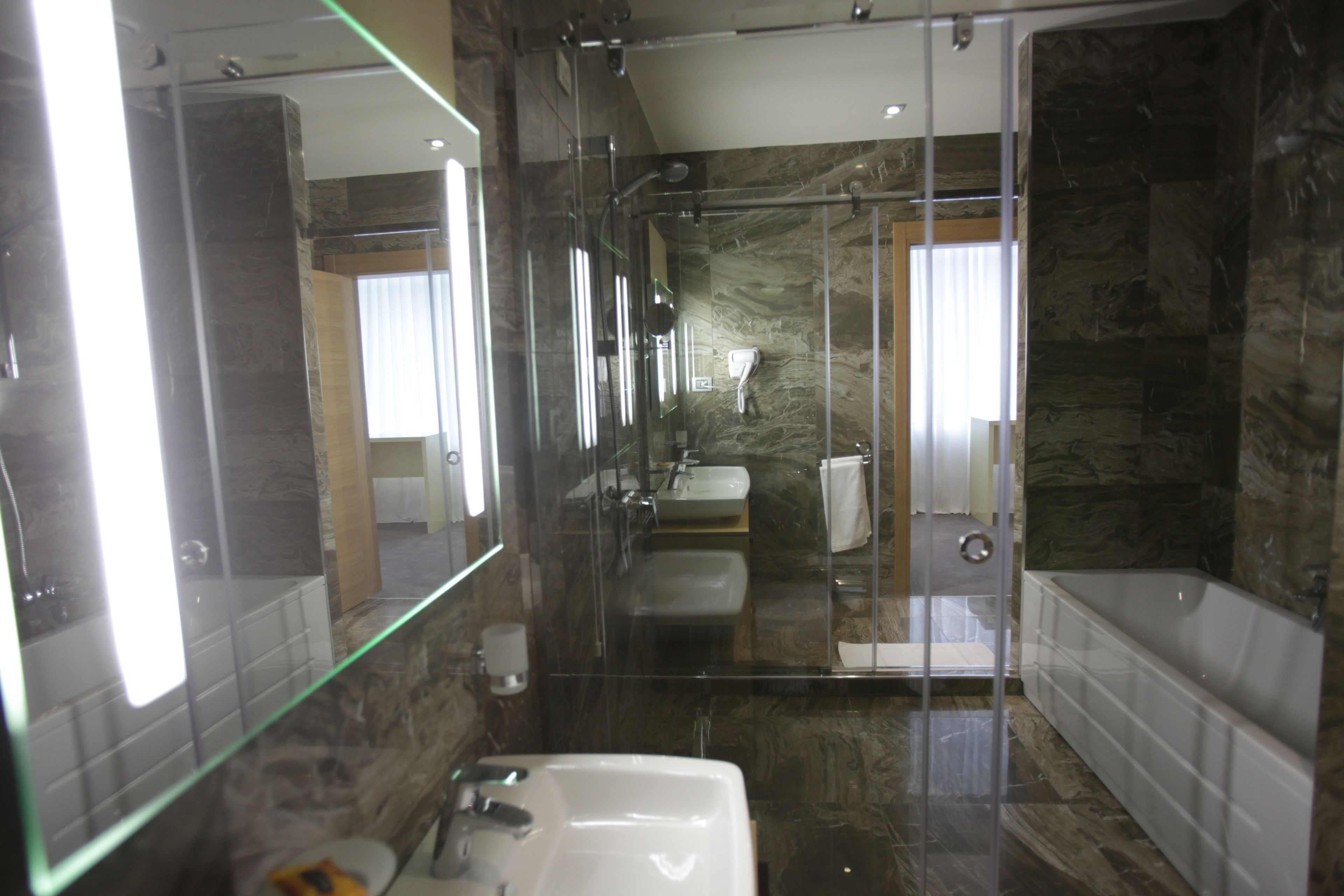 A modern bathroom with a glass-enclosed shower, a white sink, and a bathtub.