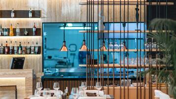 A modern restaurant with a bar area, wooden decor, and pendant lighting.