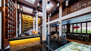 A spacious lobby with a central staircase, a reception desk, and a seating area with traditional chairs.