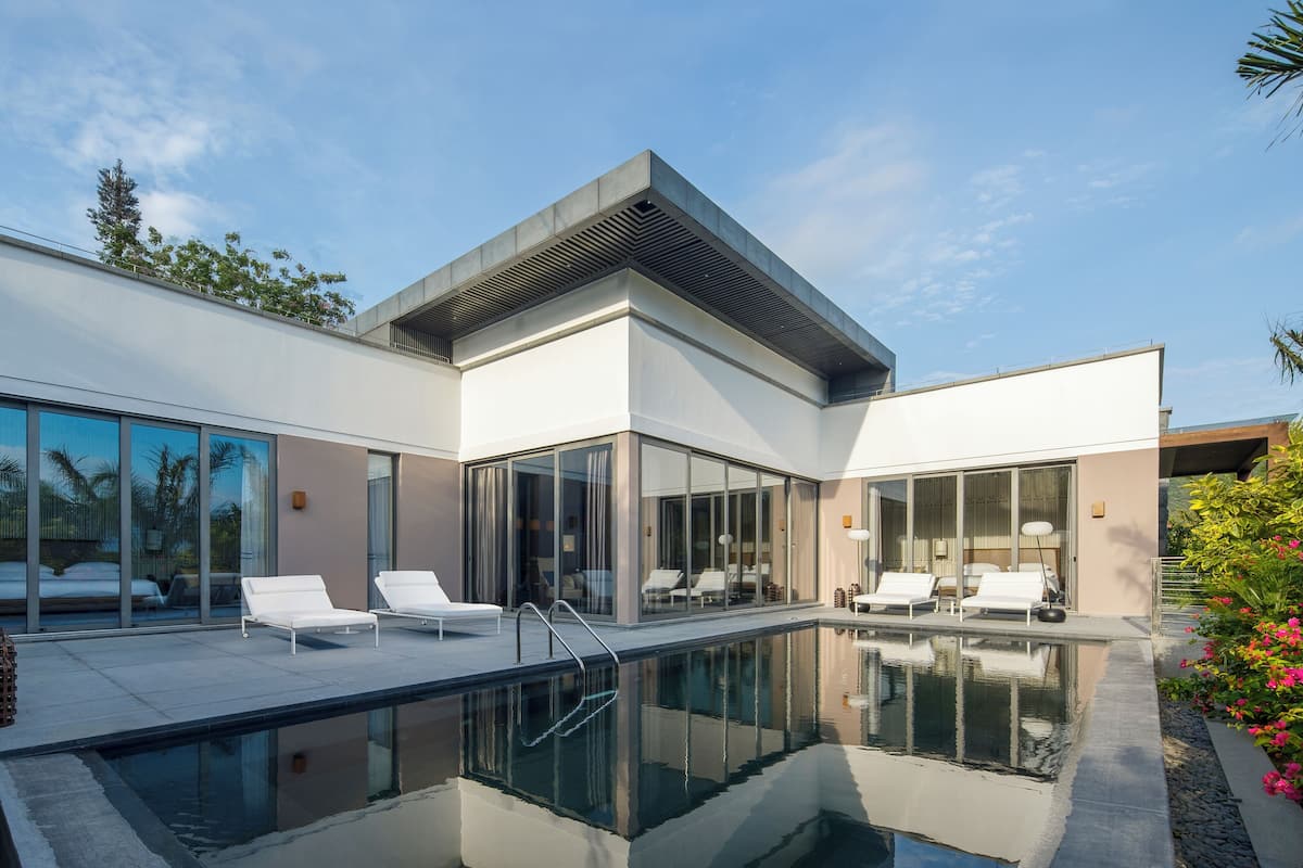 A modern house with a swimming pool, large glass windows, and outdoor seating.