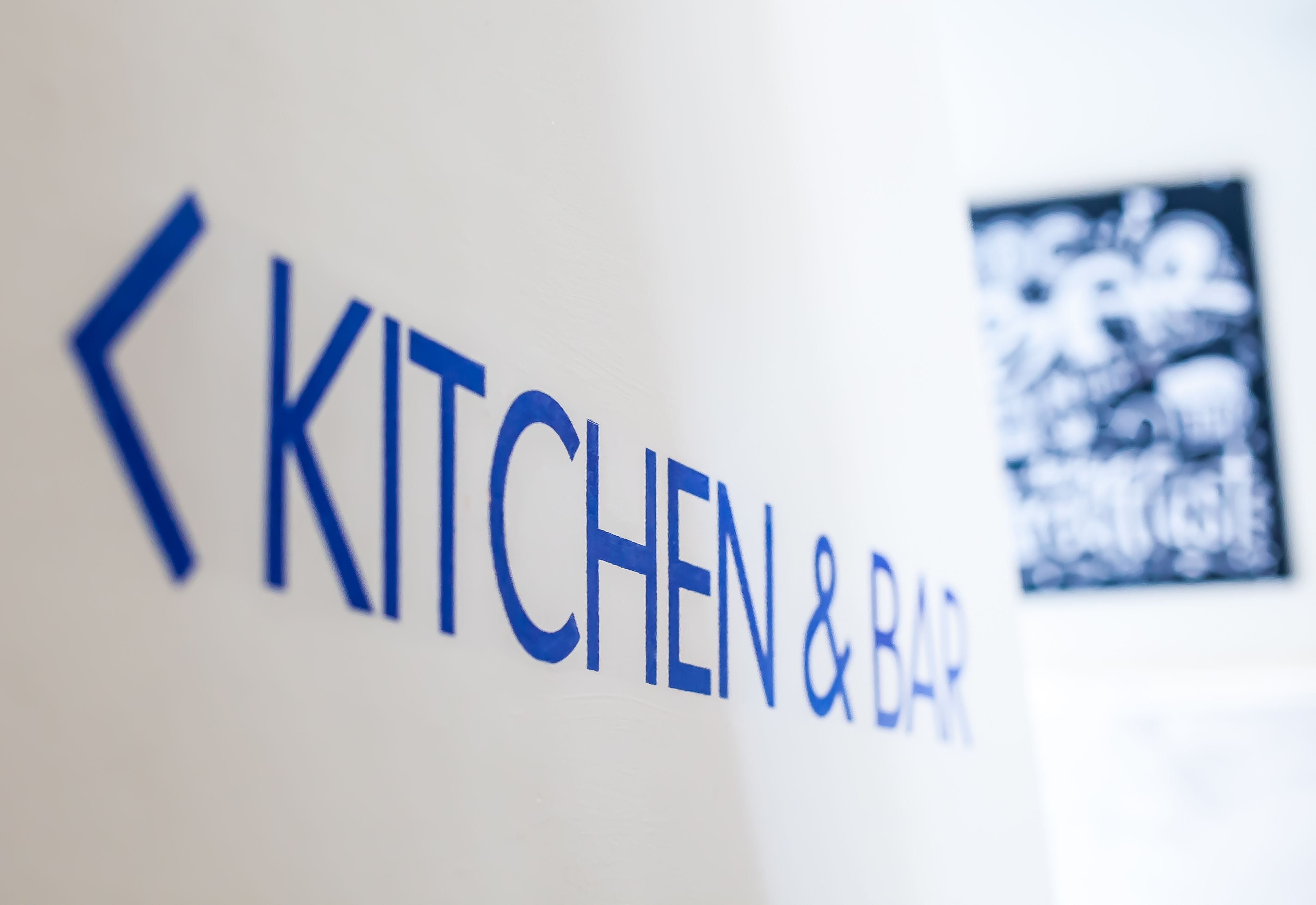 A wall with the text "KITCHEN & BAR" indicating the location of the kitchen and bar area.