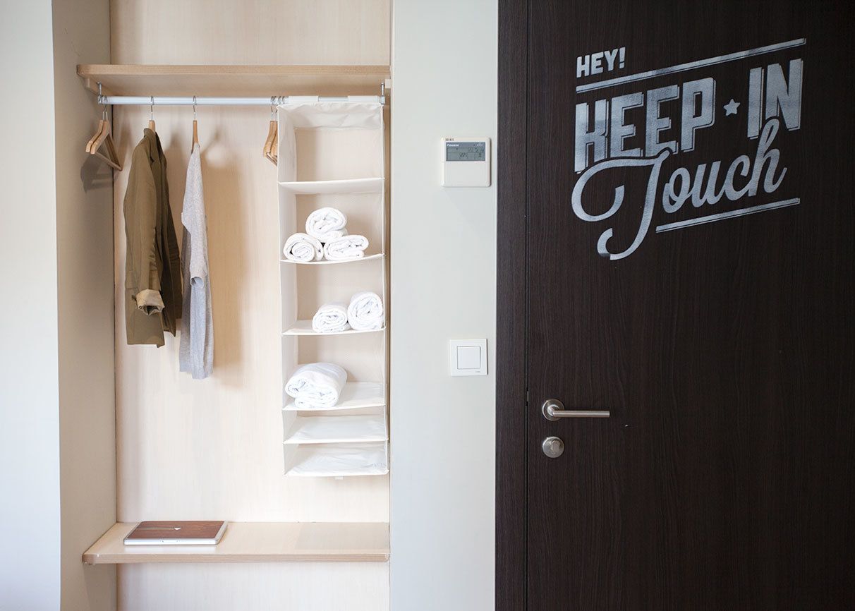 A closet with hanging clothes and shelves holding folded clothes and towels.