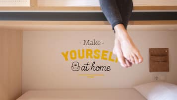 Una cama con un adhesivo en la pared que dice "Hazte COMO en casa".