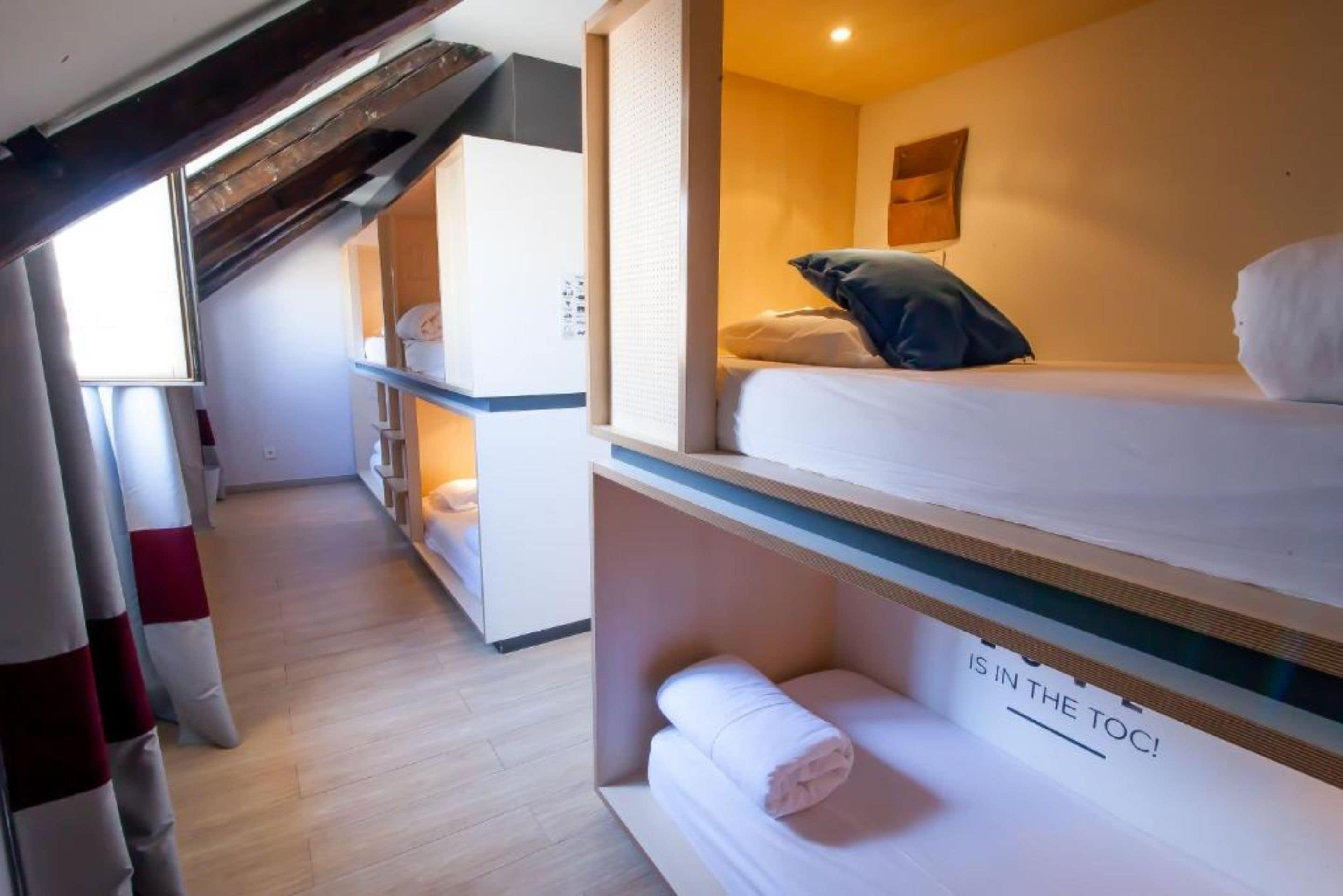 A compact hotel room with bunk beds, a small kitchenette, and a visible toilet.