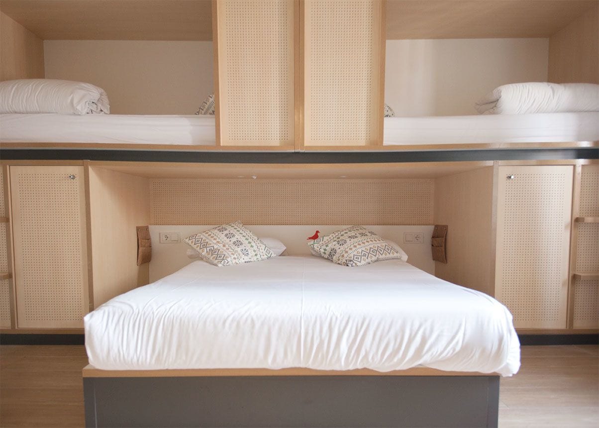 A bunk bed with a lower bunk and a single bed below. There are two pillows on the lower bunk.