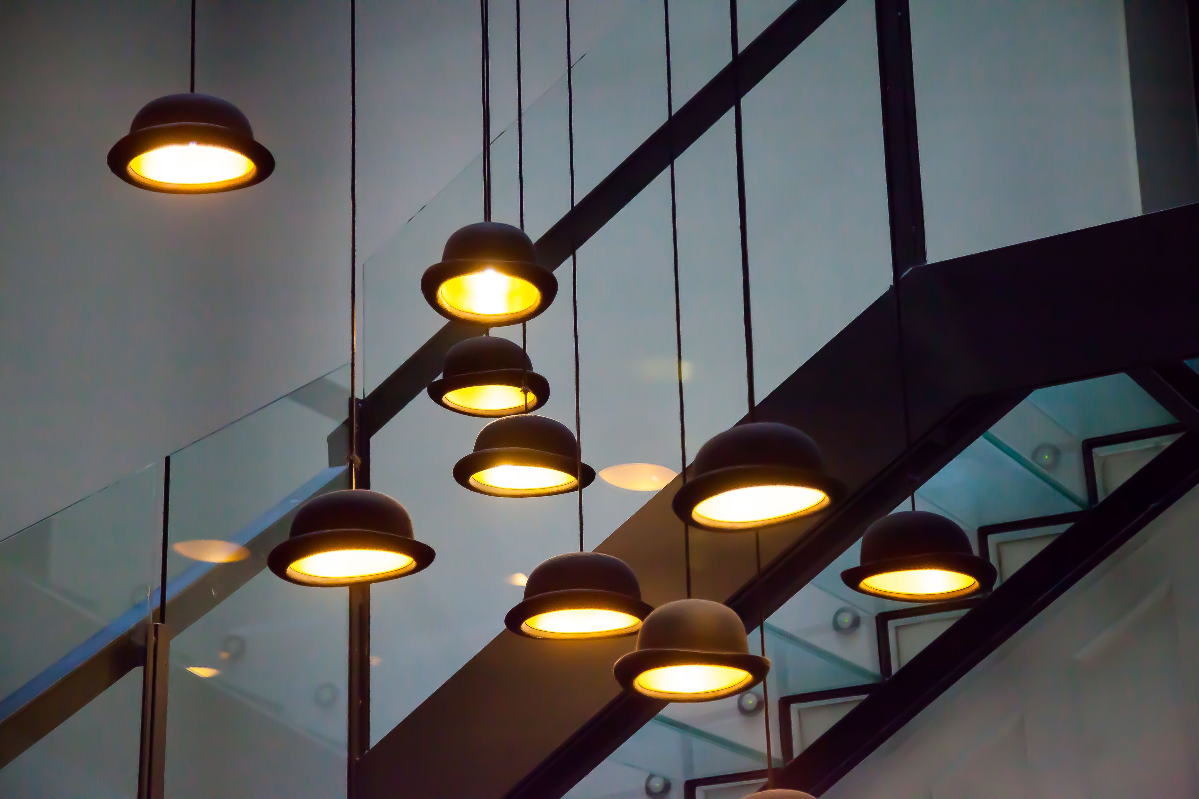 A modern interior with multiple hanging pendant lights and a glass staircase.