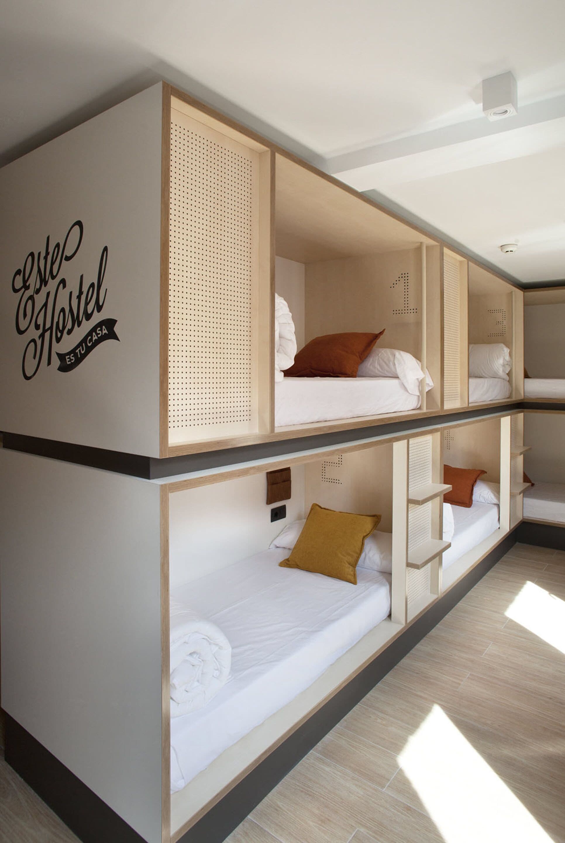 Une chambre d’auberge de jeunesse avec des lits superposés, un mur orné d’une affiche et un plancher en bois.