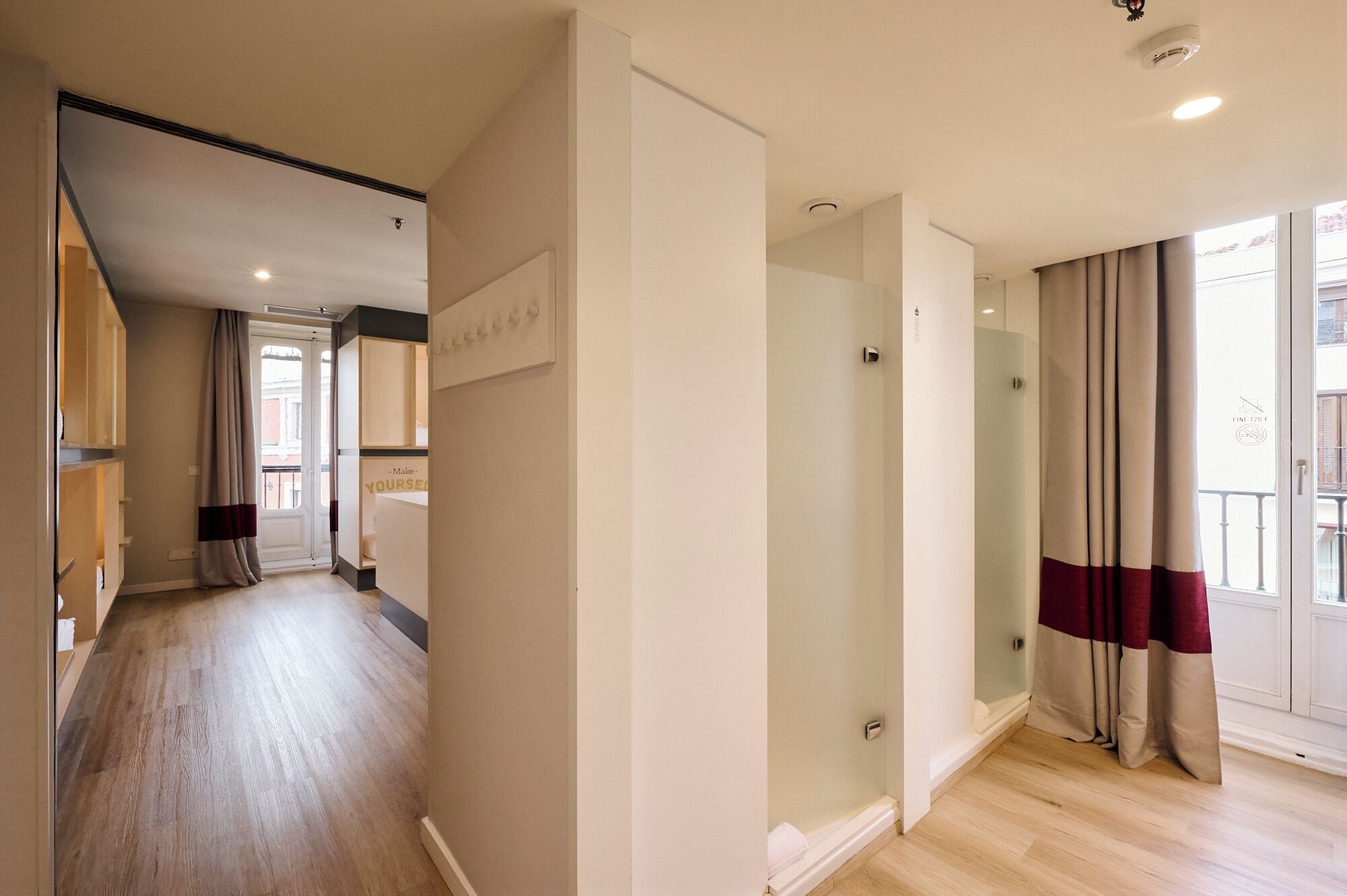 Eine moderne Wohnung mit Holzboden, einer Glasdusche und Blick auf die Stadt durch große Fenster.