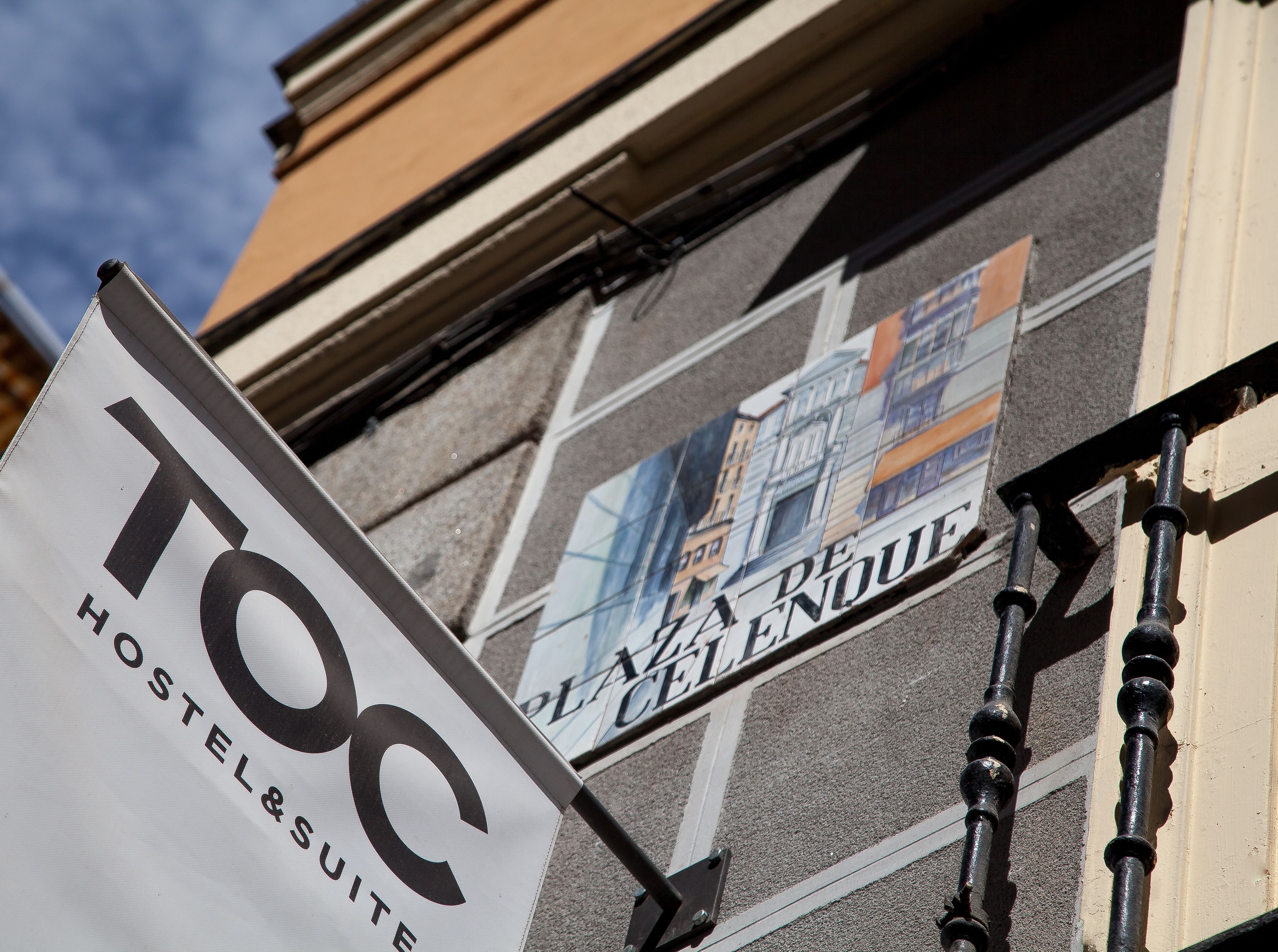 Cartell de 'TOC Hostel & Suites' amb edificis al fons.