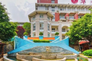 A hotel with a fountain, a multi-level structure, and a red building in the background.