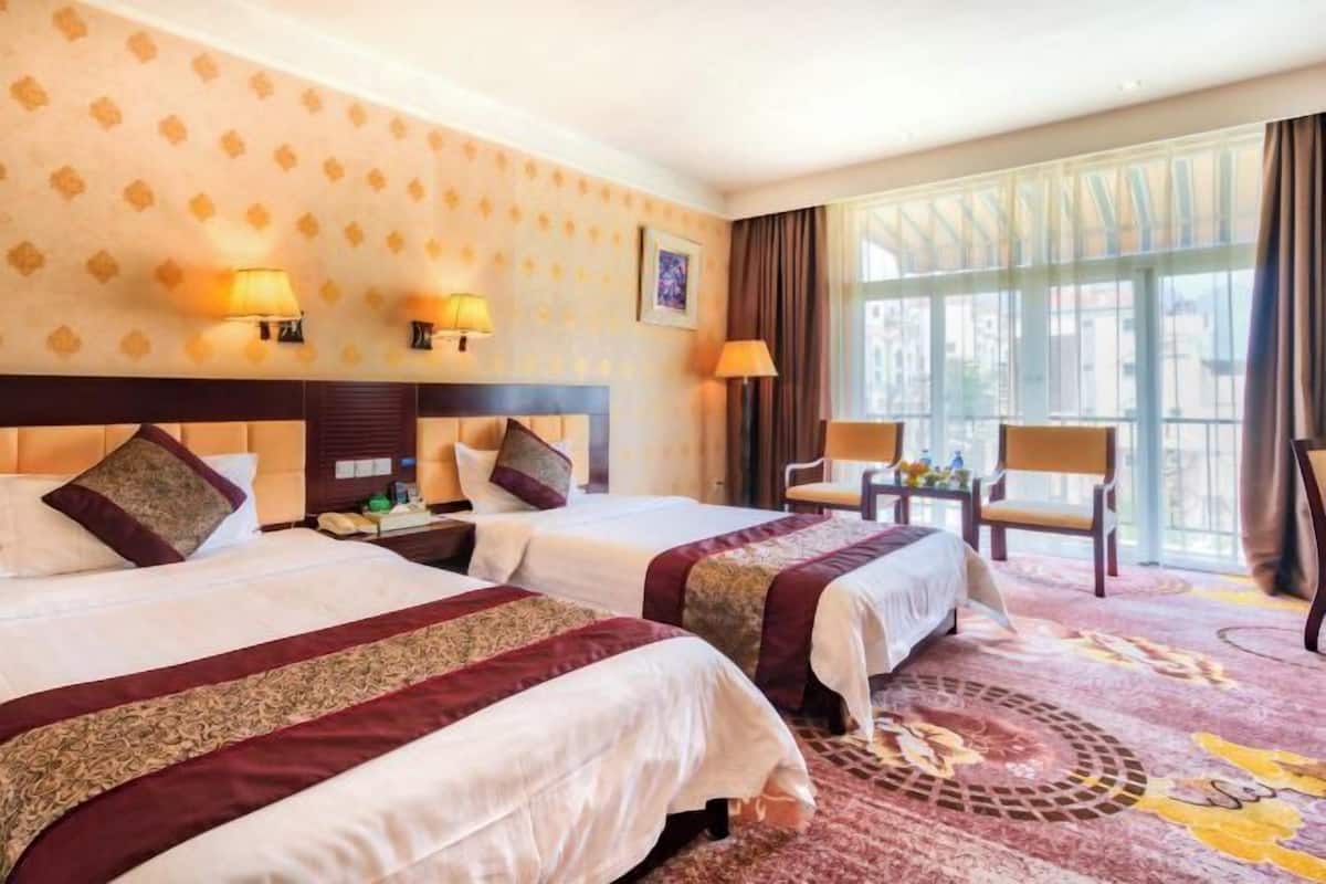A hotel room with two beds, a large window, and a view of the city.