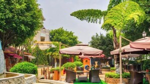 An outdoor patio area with stone planters, a small water feature, and outdoor seating under umbrellas. - Hua Xi Hotel (Wenshan City)