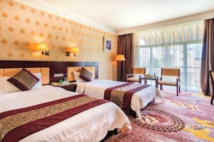 A hotel room with two beds, a large window, and a view of the city.