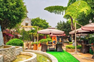 An outdoor patio area with a fountain, seating, and umbrellas.