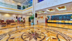 A spacious lobby with a marble floor, a reception desk, and a high ceiling with skylights. - Hua Xi Hotel (Wenshan City)