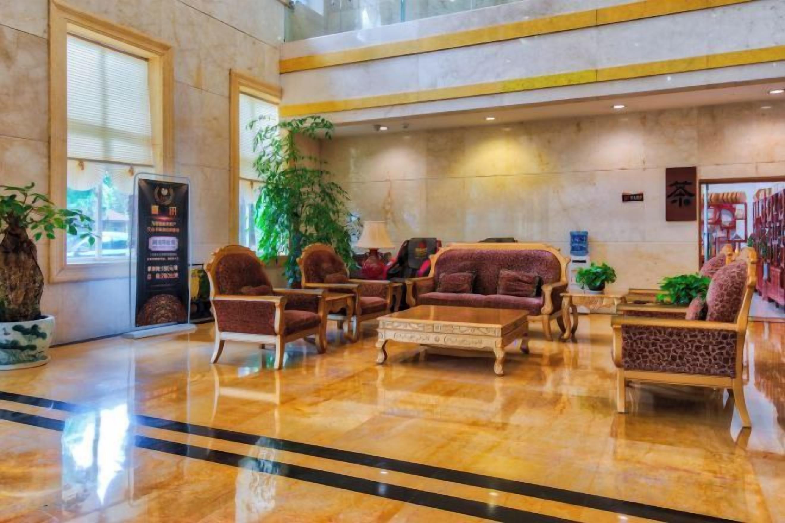 A lobby with seating arrangements, a reception desk, and a large potted plant.