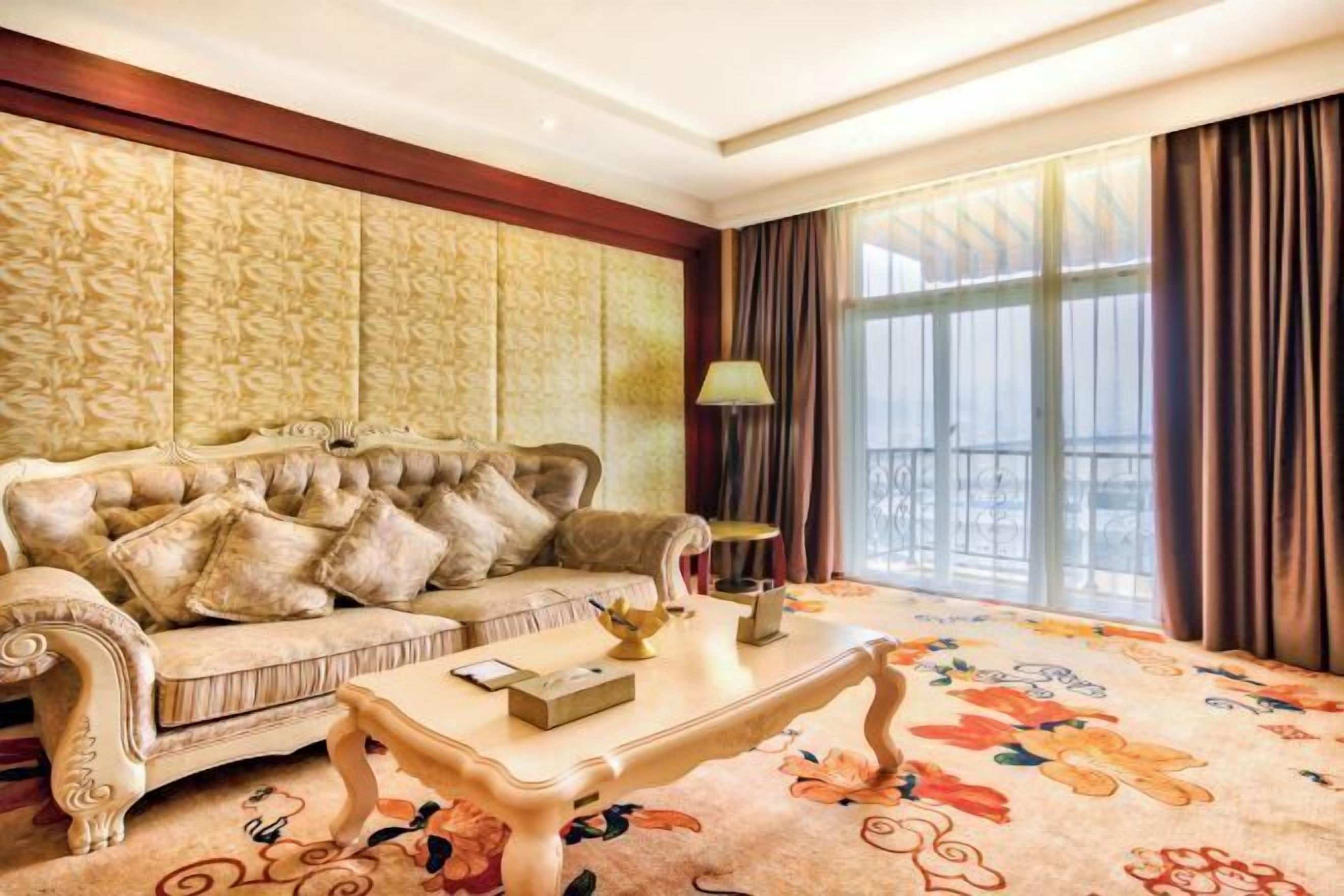 A room with a tufted sofa, a table, and a floral carpet.