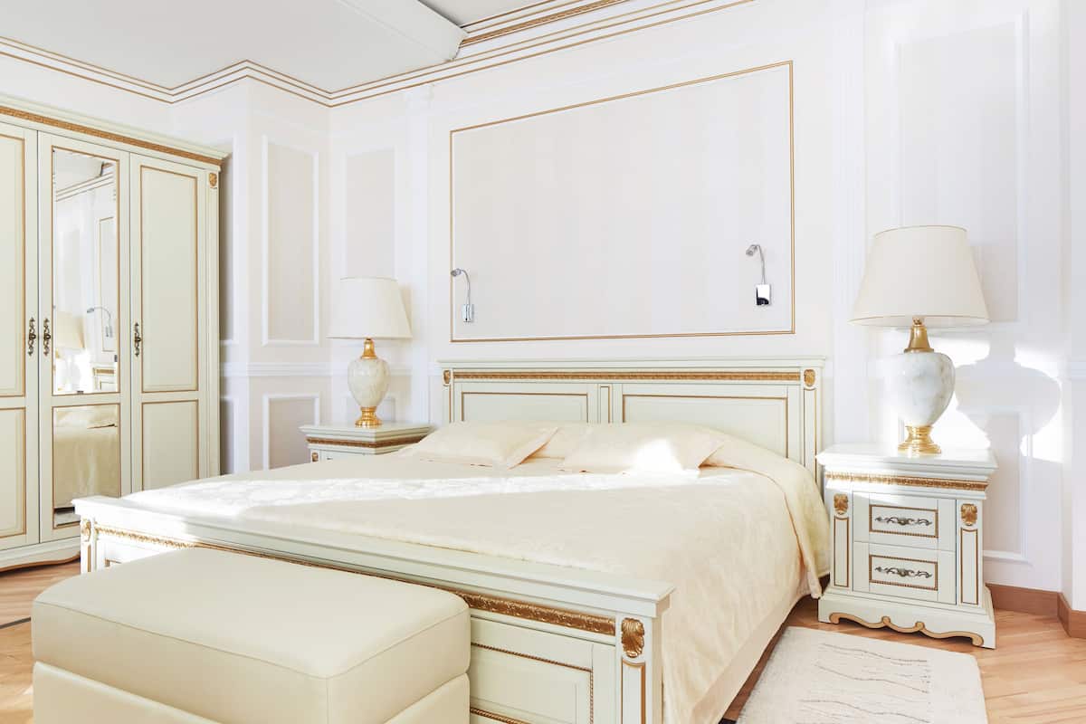 A bedroom with a large bed, bedside tables, a nightstand, a mirror, and a wardrobe.