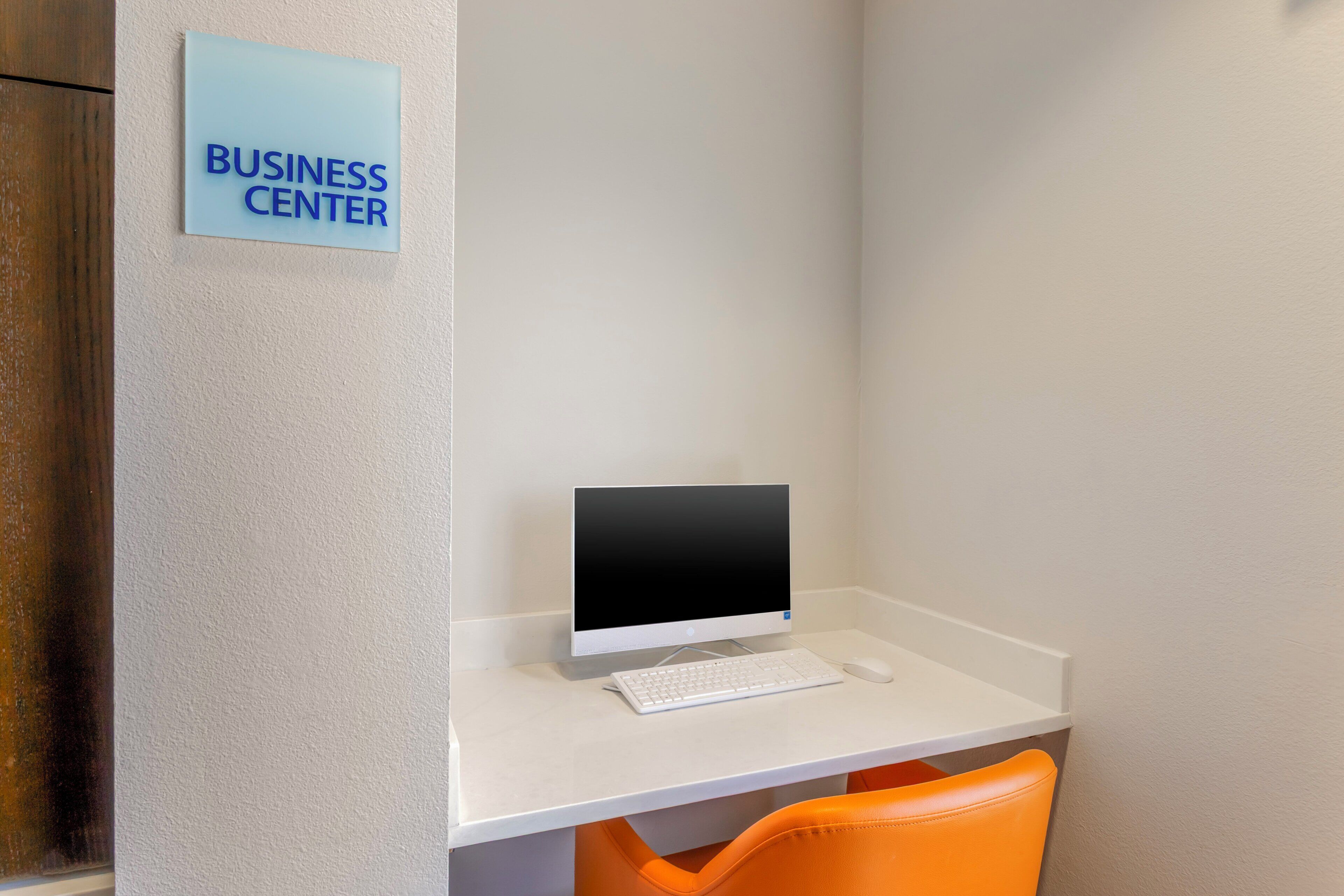 Un centro de negocios con un escritorio, un teclado, un ratón y una silla naranja.