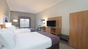 A hotel room with two beds, a desk, a television, and a wardrobe.