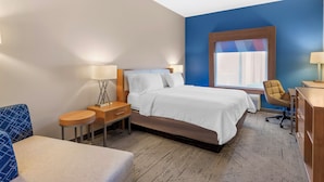Ett hotellrum med en säng, sängbord, ett skrivbord, en stol och ett fönster.