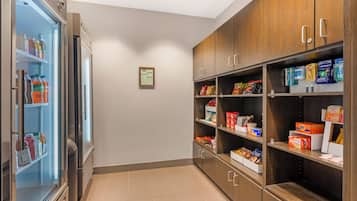 Una kitchenette equipada con un refrigerador lleno de bebidas, un microondas y un lavabo.