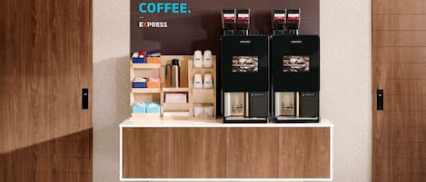 Una estación de café con dos máquinas de café, una variedad de cápsulas y tazas.