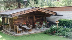 Uma cabana de madeira rústica com varanda, uma bicicleta e um bebedouro para pássaros.