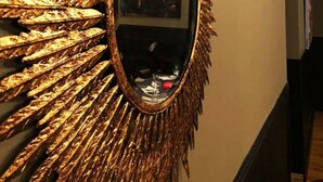 Un couloir orné d’un grand miroir décoratif au motif rayonnant.