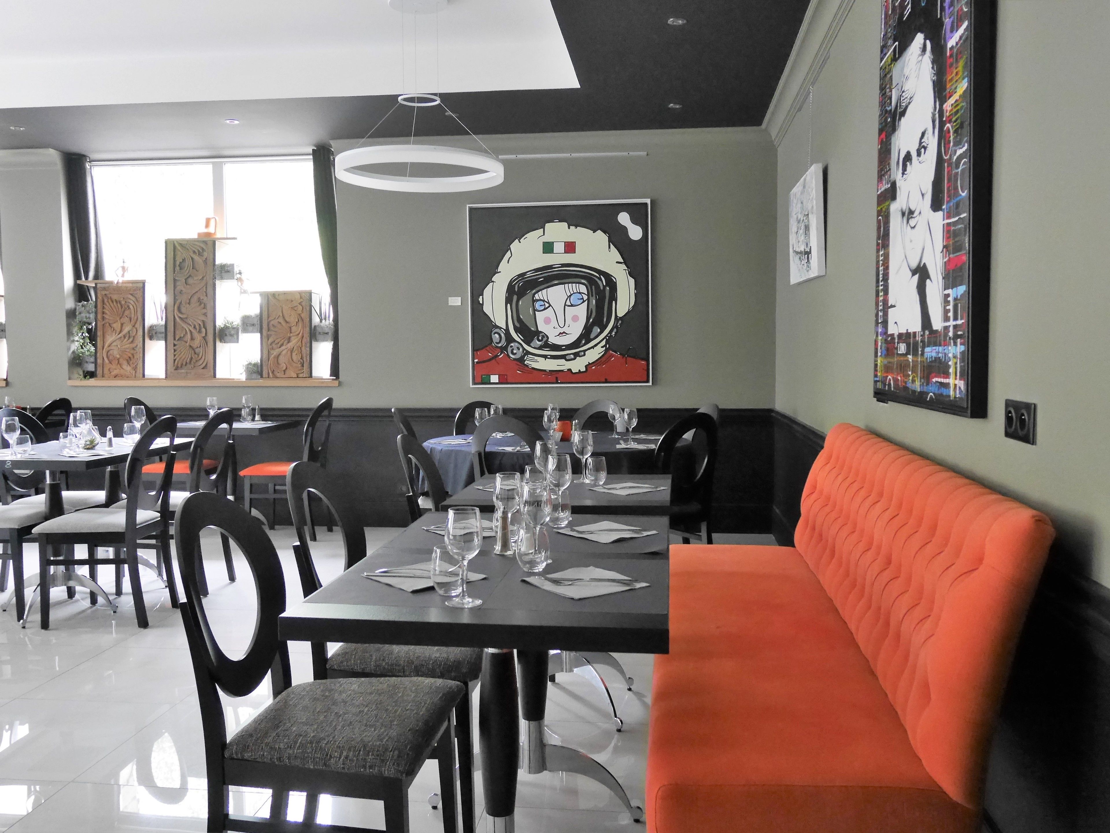 A modern dining area with tables set for dining, chairs, and a sofa.
