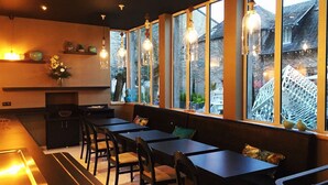 Un restaurant moderne doté d’un long comptoir, de nombreuses tables et de bancs. De grandes fenêtres offrent une vue sur l’extérieur.