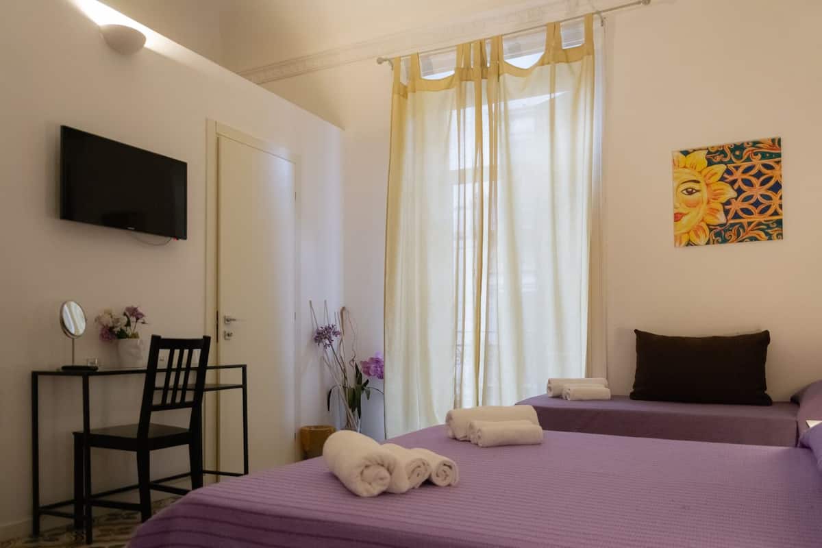 Habitación de hotel con dos camas, un televisor, un escritorio con silla y un cuadro en la pared.